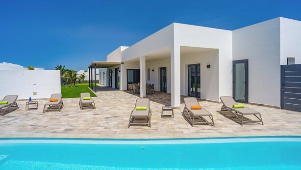 A modern resort with a pool area, outdoor seating, and a covered patio. - Villa Tirma by Villa Plus (Playa Blanca)