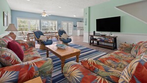 A living room with a large TV, two blue armchairs, a wooden coffee table, and a colorful sofa. - Indulge in the epitome of coastal living with Celtic Dream-pool (North Myrtle Beach)