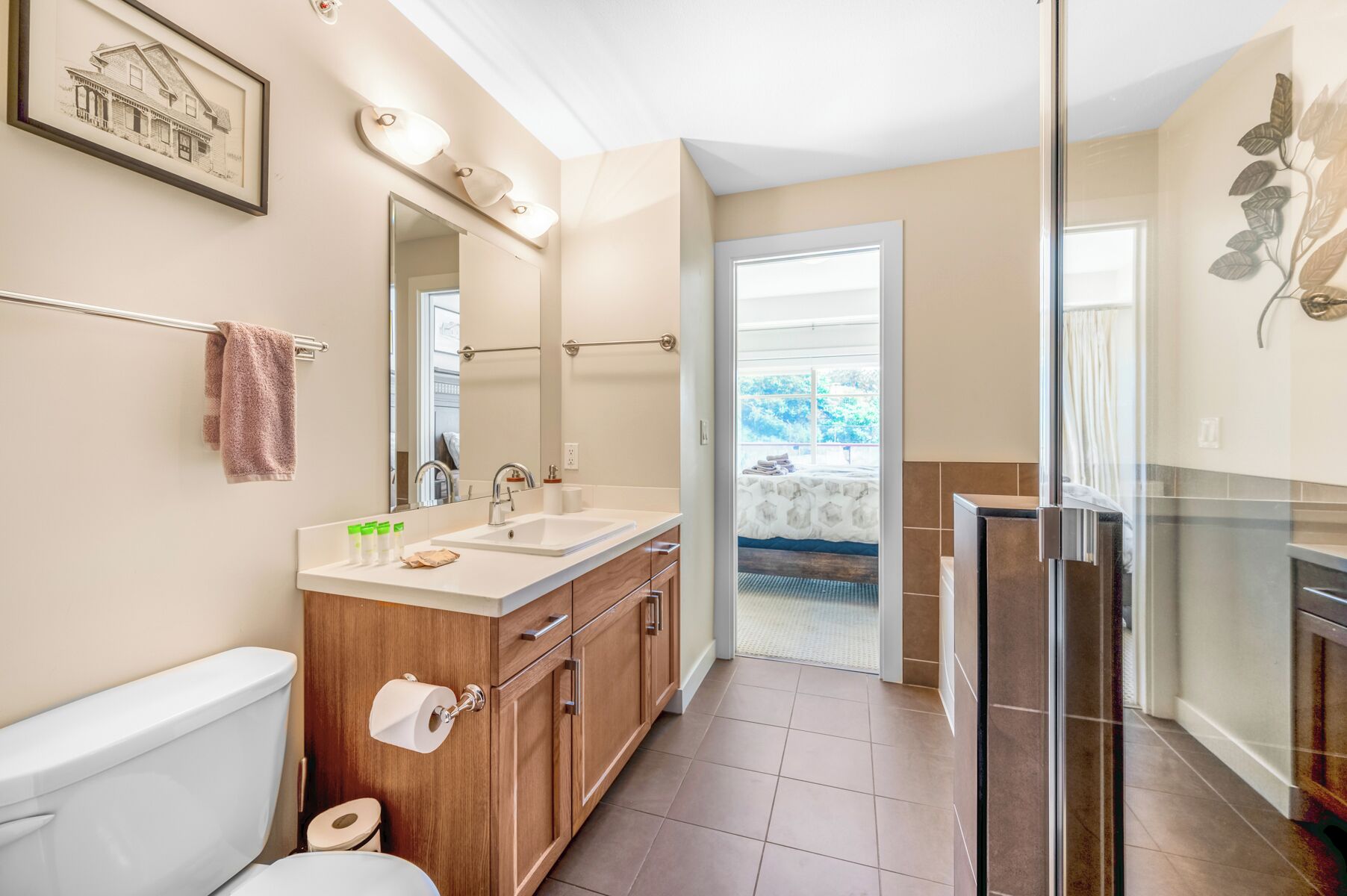 A bathroom with a white sink, wooden cabinets, a large mirror, and a glass shower enclosure.