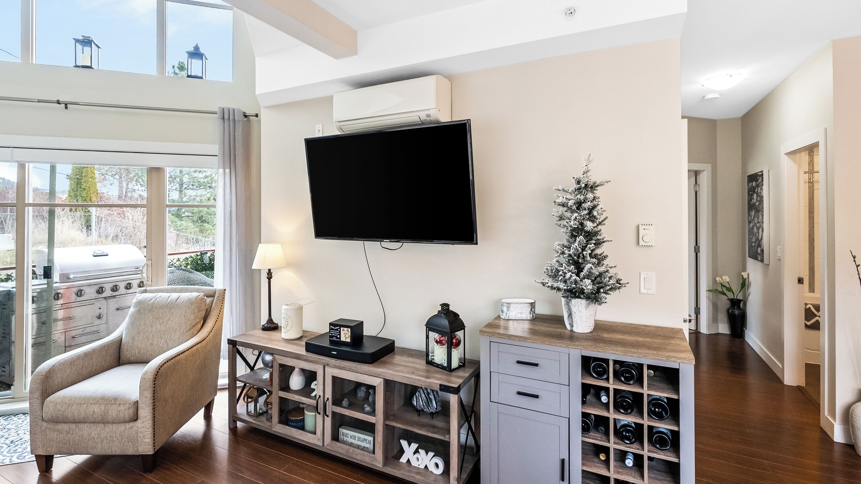 Ein Wohnzimmer mit Fernseher, Weihnachtsbaum, Weinkühler und einem gemütlichen Sessel.