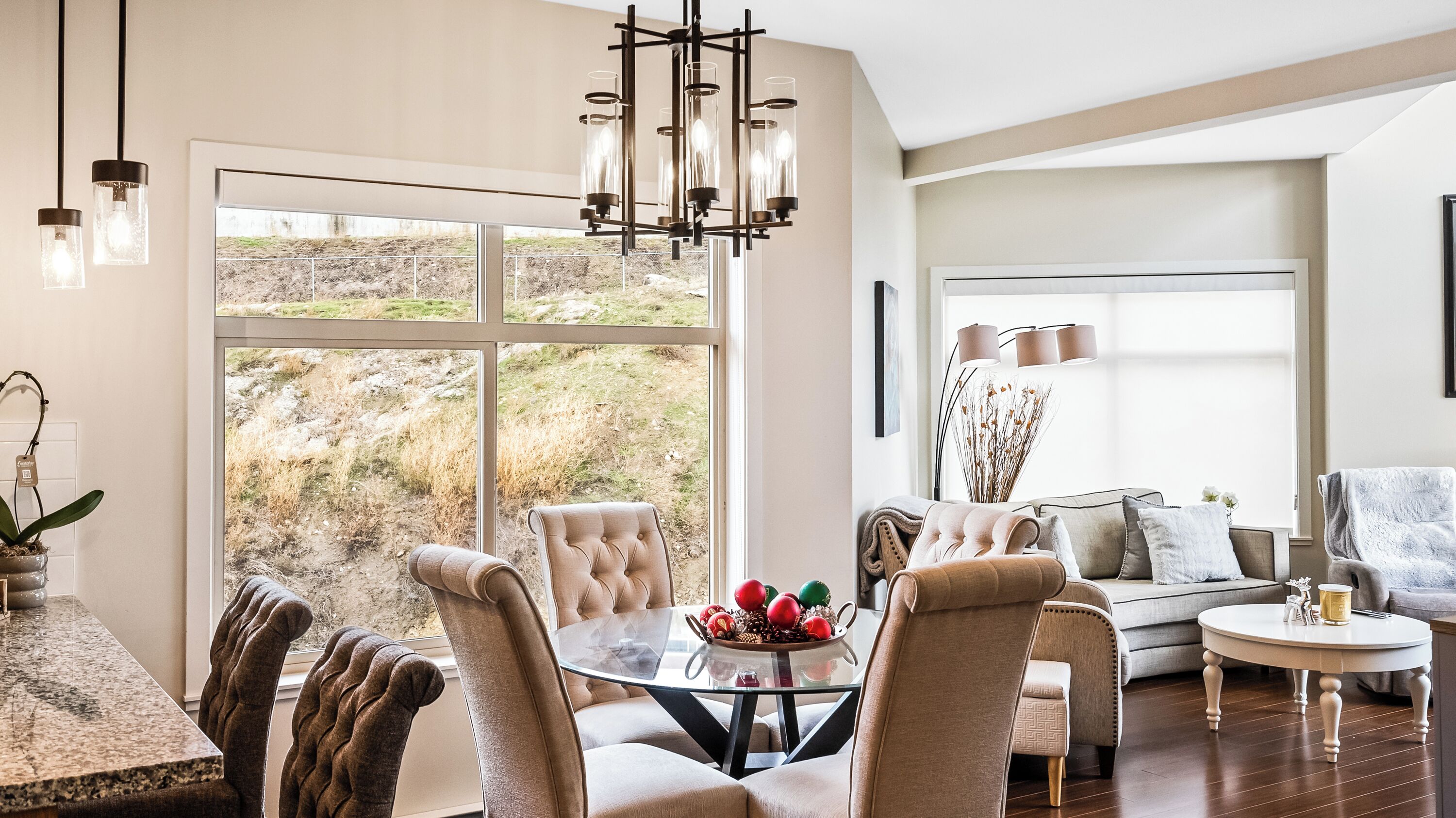 Un salón amplio con un gran ventanal, un comedor con mesa de cristal y una zona de estar acogedora con sofá y sillones.