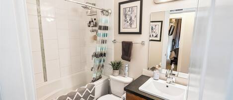 A modern bathroom with a shower, toilet, sink, and vanity.