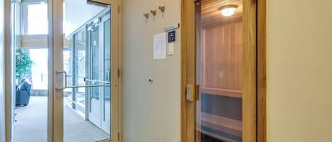 Entrada de un hotel con puerta de vidrio, señal de salida y puerta de madera que conduce a una sauna.