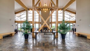 A spacious lobby with a high ceiling, wooden beams, and large windows. - Top Floor Lake View Condo at Copper Sky (West Kelowna)