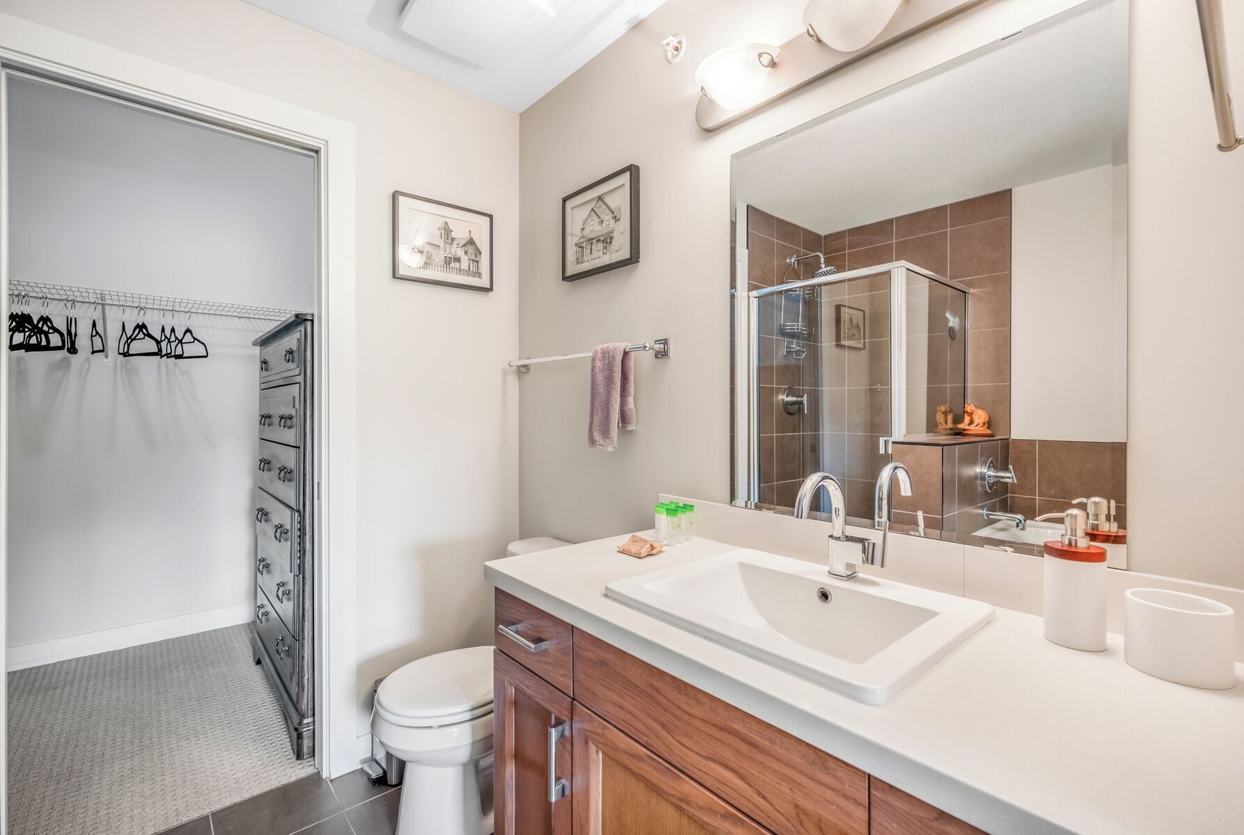 Een moderne badkamer met een grote spiegel, een douche en een wastafelmeubel met een wastafel en kast.