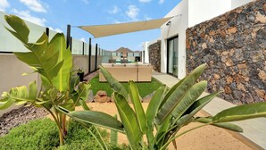 Un espace extérieur moderne aménagé avec des sièges, un mur en pierre et une grande plante au premier plan.