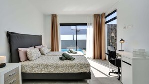 Une chambre moderne avec un grand lit, un bureau et une vue sur une piscine.