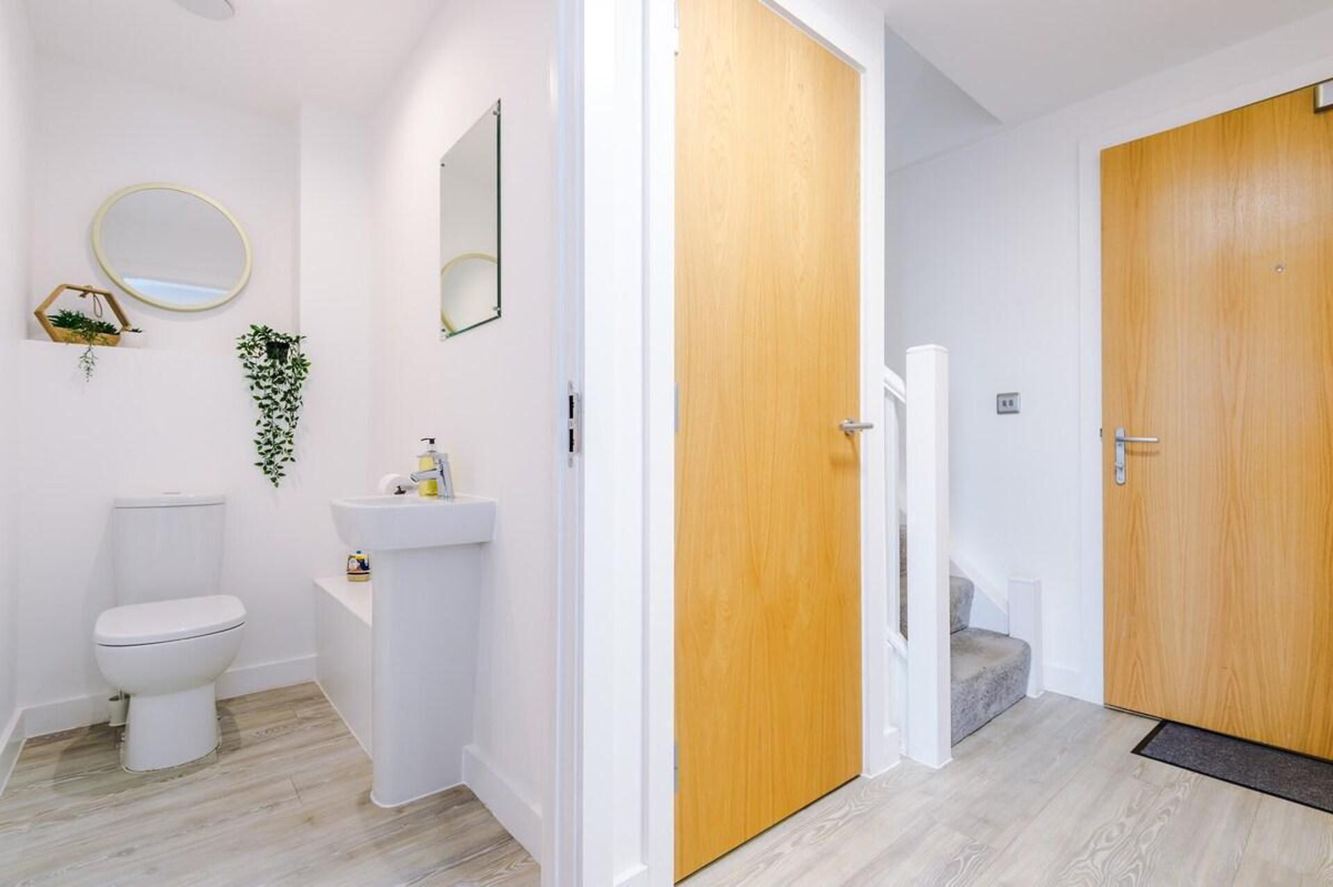 A modern bathroom with a toilet, sink, and two wooden doors.