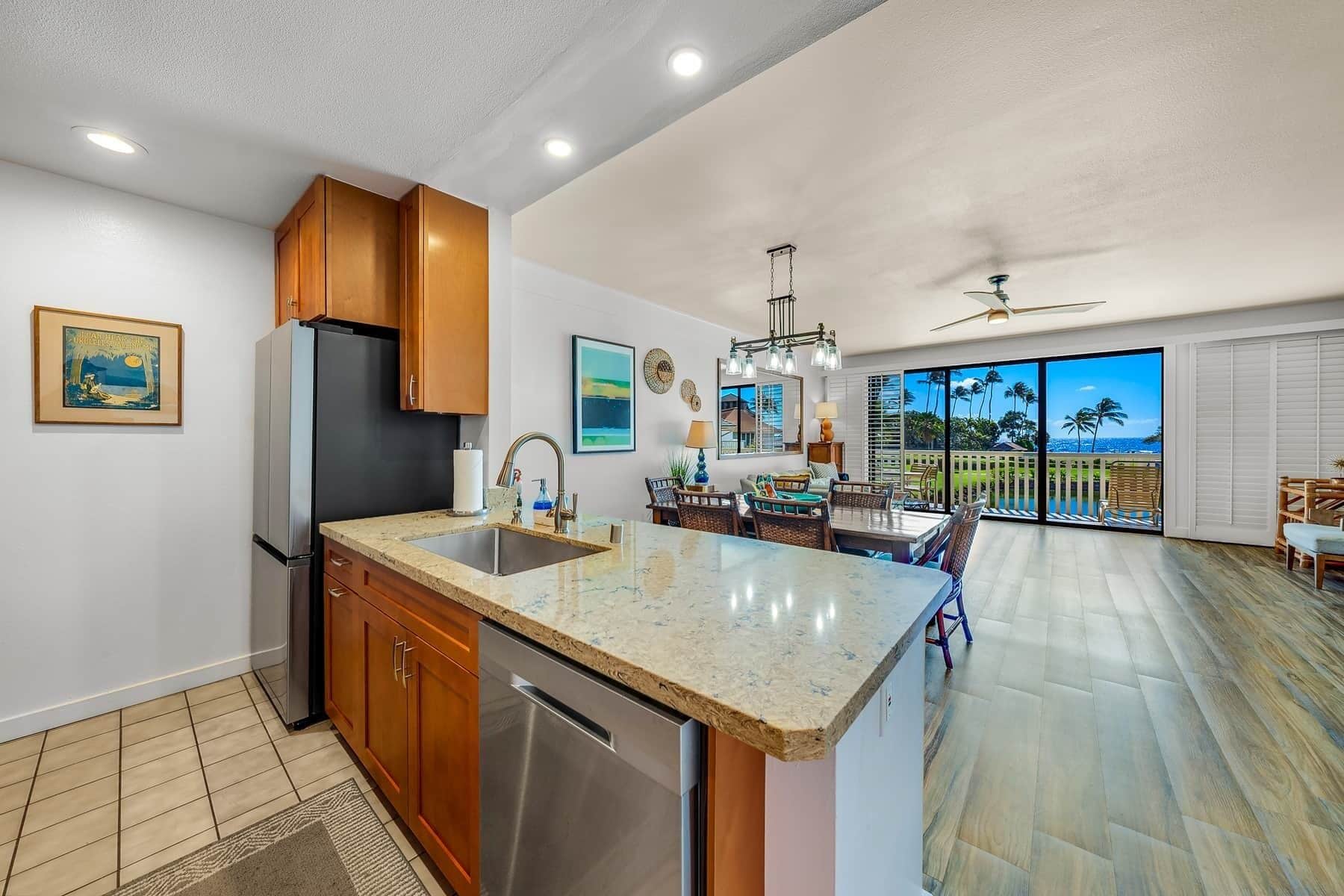 A kitchen with a large island, wooden cabinets, and a view to the outside.