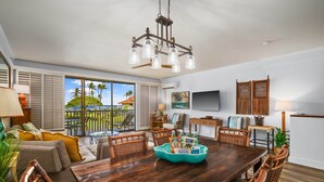 A dining area with a wooden table, wicker chairs, a chandelier, and a view of the outdoors.