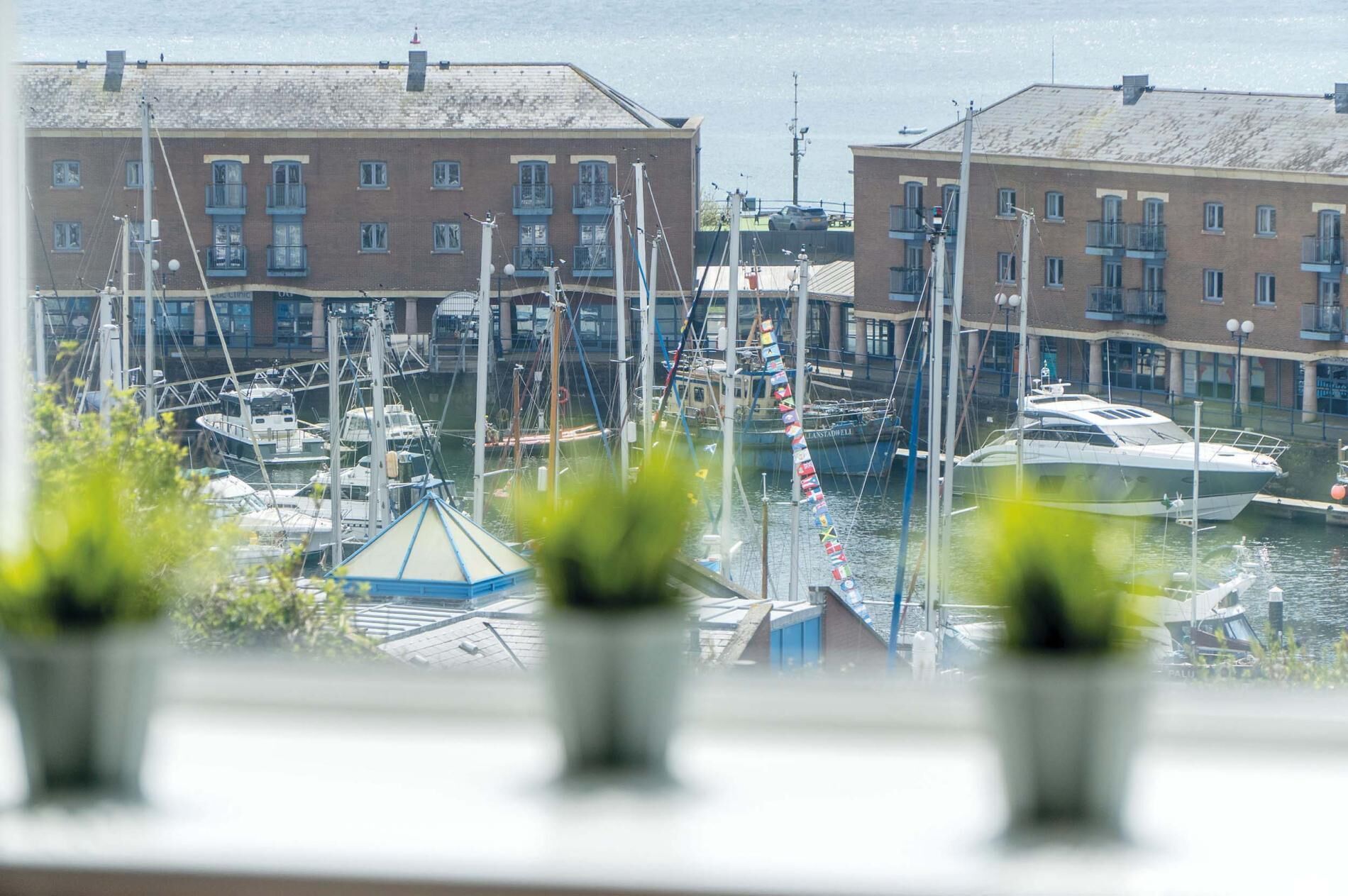 A marina with boats docked, buildings with multiple windows, and a clear view of the water.