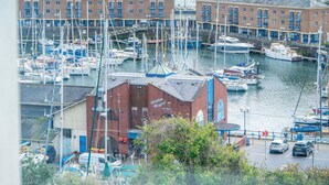 A marina with boats docked, a building labeled 'Marshalls Vineyard', and a parking area with cars.