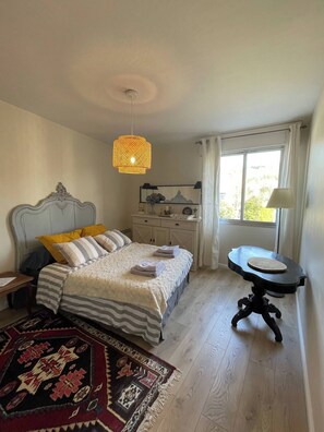 Enjoy a restful stay in this cozy retreat with a neatly made bed, a woven pendant light, and a view of the outdoors.