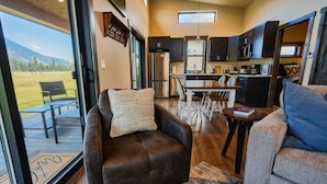 A modern RV interior with a living area, kitchen, and dining space.