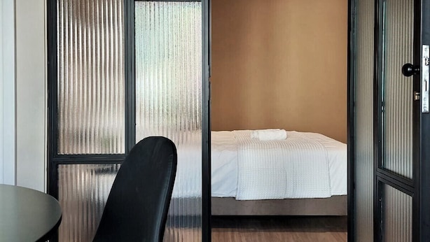 A compact room with a bed, a chair, and a table. - Terrazzo City Apts (Heraklion)