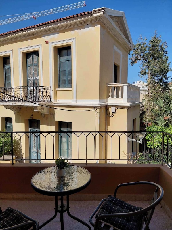 A two-story building with a balcony, a table, and two chairs.