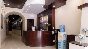 Una zona de recepción con un mostrador de madera, un dispensador de agua y un cartel en la pared.
