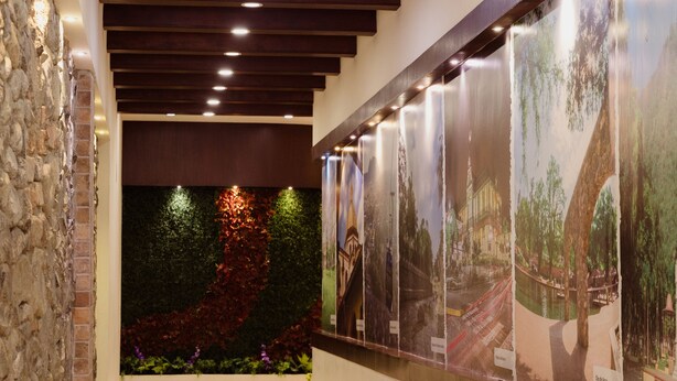 Un pasillo con paredes de piedra, iluminación empotrada y una exposición de carteles de viajes en la pared.