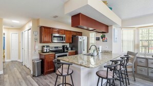 A modern kitchen with granite countertops, stainless steel appliances, and a central island with bar stools.