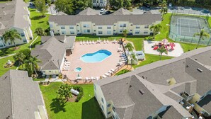 A multi-story hotel with a central pool area surrounded by lounge chairs and a children's play area.