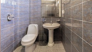 A bathroom with a toilet, sink, and mirror. - New Beachscape (Jeju City)