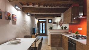 A modern kitchen with wooden cabinets, a stove, and a dining area with a table and chairs.