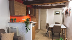 A compact kitchen with wooden cabinets, a dining area with a table and chairs, and a radiator.