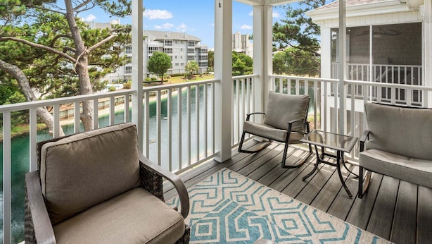 A covered outdoor deck with a view of a body of water and buildings in the background. - Rare find in the heart of North Myrtle Beach (North Myrtle Beach)