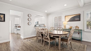 A dining area with a round table, chairs, a rug, a kitchen in the background, and a painting on the wall. - Rare find in the heart of North Myrtle Beach (North Myrtle Beach)