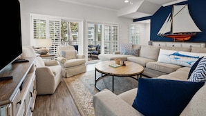 A living room with a TV, sofa, armchairs, a coffee table, and a sailboat decoration on the wall. - Rare find in the heart of North Myrtle Beach (North Myrtle Beach)