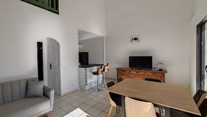 A compact living space with a sofa, a dining table, a TV, and a kitchenette. - Villa Familiale Superbe vue mer et Couchers de Soleil (Pietrosella)