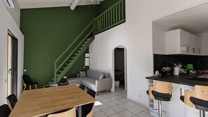 A modern apartment with a dining area, a sofa, a staircase, and a kitchen. - Villa Familiale Superbe vue mer et Couchers de Soleil (Pietrosella)