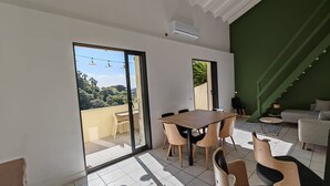A modern living room with a dining area, large windows, and a staircase. - Villa Familiale Superbe vue mer et Couchers de Soleil (Pietrosella)