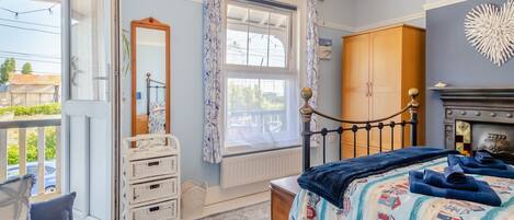 Un dormitorio con cama, cómoda, espejo y vistas al exterior.