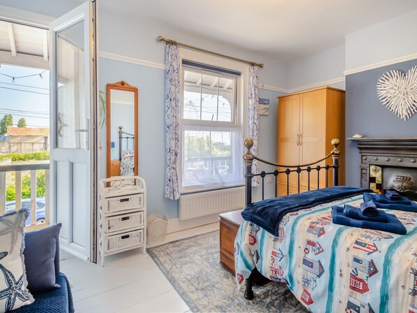 A bedroom with a bed, dresser, mirror, and a view of the outside.