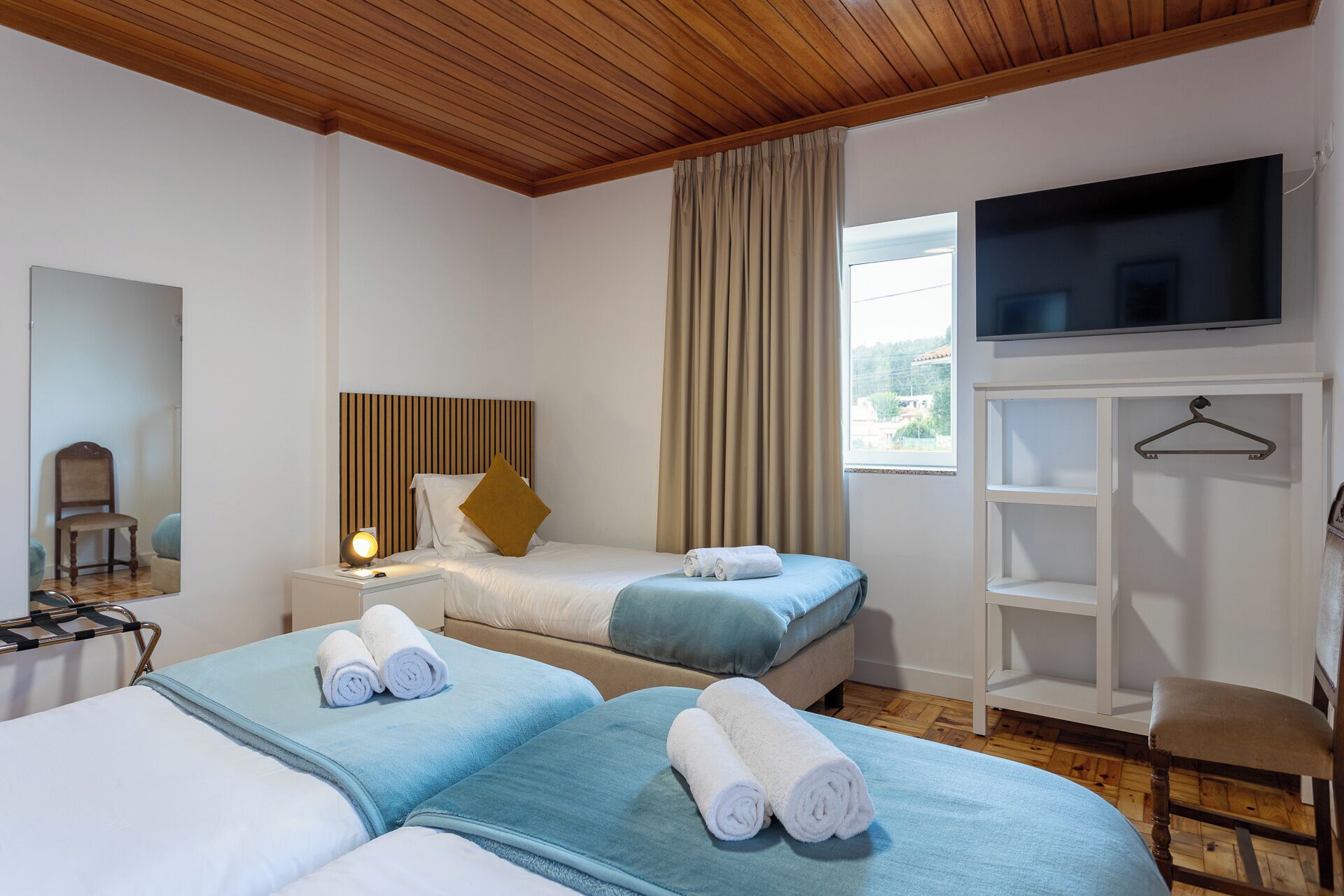 Ein Hotelzimmer mit zwei Betten, einem Fernseher, einem Kleiderschrank und einem Sessel.