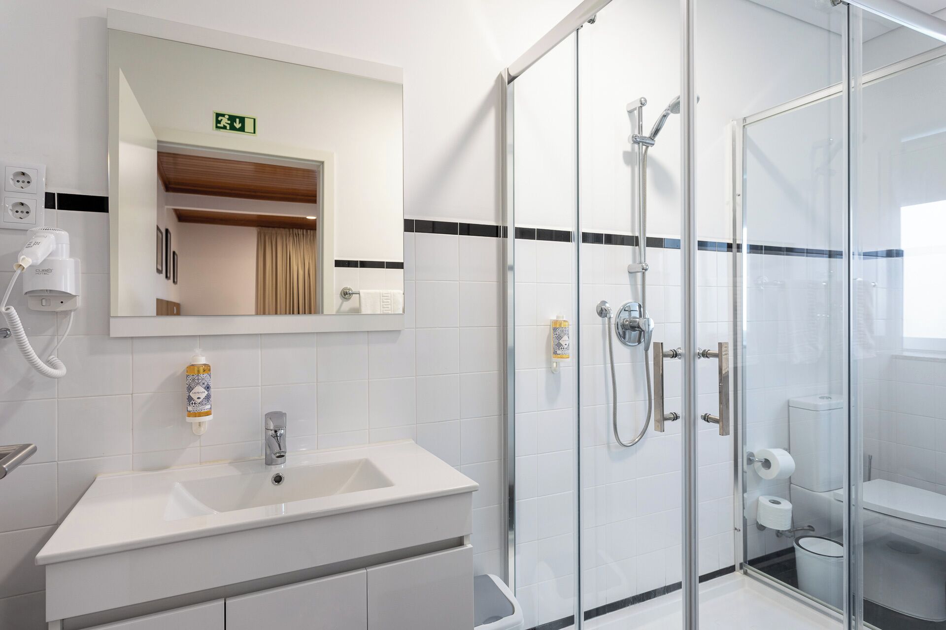 Un baño moderno con cabina de ducha de vidrio, un lavabo blanco y un espejo sobre él.