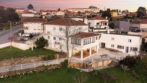 A residential area with houses, a paved road, and a grassy area with trees. - Guest House A Loja do Cantoneiro (Albergaria-a-Velha)