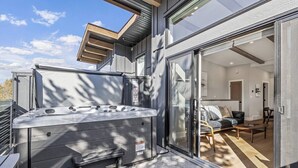 A modern outdoor hot tub area with a glass door leading to a living room.