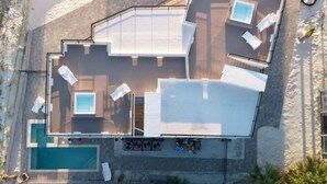 Eine Vogelperspektive eines modernen Hotels mit mehreren Stockwerken, einem Schwimmbad und Sitzbereichen im Freien.