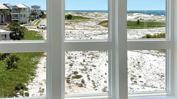 Ein Zimmer mit großem Fenster und Blick auf Strand und Häuser.