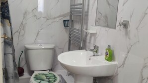 Un baño con inodoro, lavamanos y espejo.