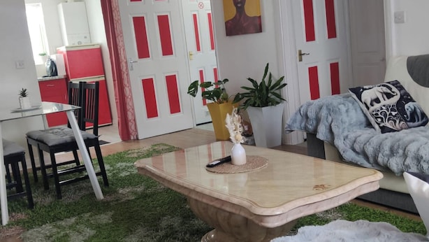 Una sala de estar con una mesa de centro de vidrio, un sofá y un comedor con una mesa y sillas.