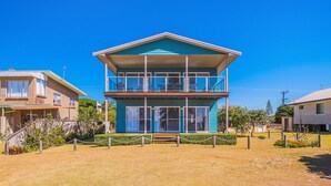 A two-story building with a balcony, surrounded by a fenced area and dry grass. - Casa della vista - Beach Front Location (Brooms Head)