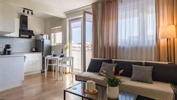 Un apartamento moderno con cocina, comedor y sala de estar. Cuenta con un sofá, una mesa de centro y vistas de la ciudad a través de amplias ventanas.