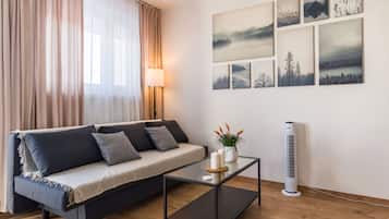 A modern living room with a sofa, a glass coffee table, and a wall-mounted air purifier.