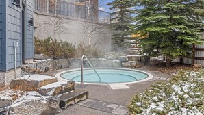 Ein Thermalbereich mit Pool, umgeben von Felsen und Bäumen.