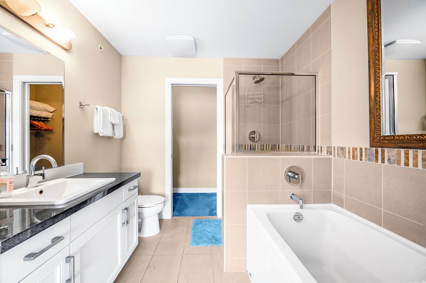 A modern bathroom with a large bathtub, a shower area, and a vanity with a sink and mirror.