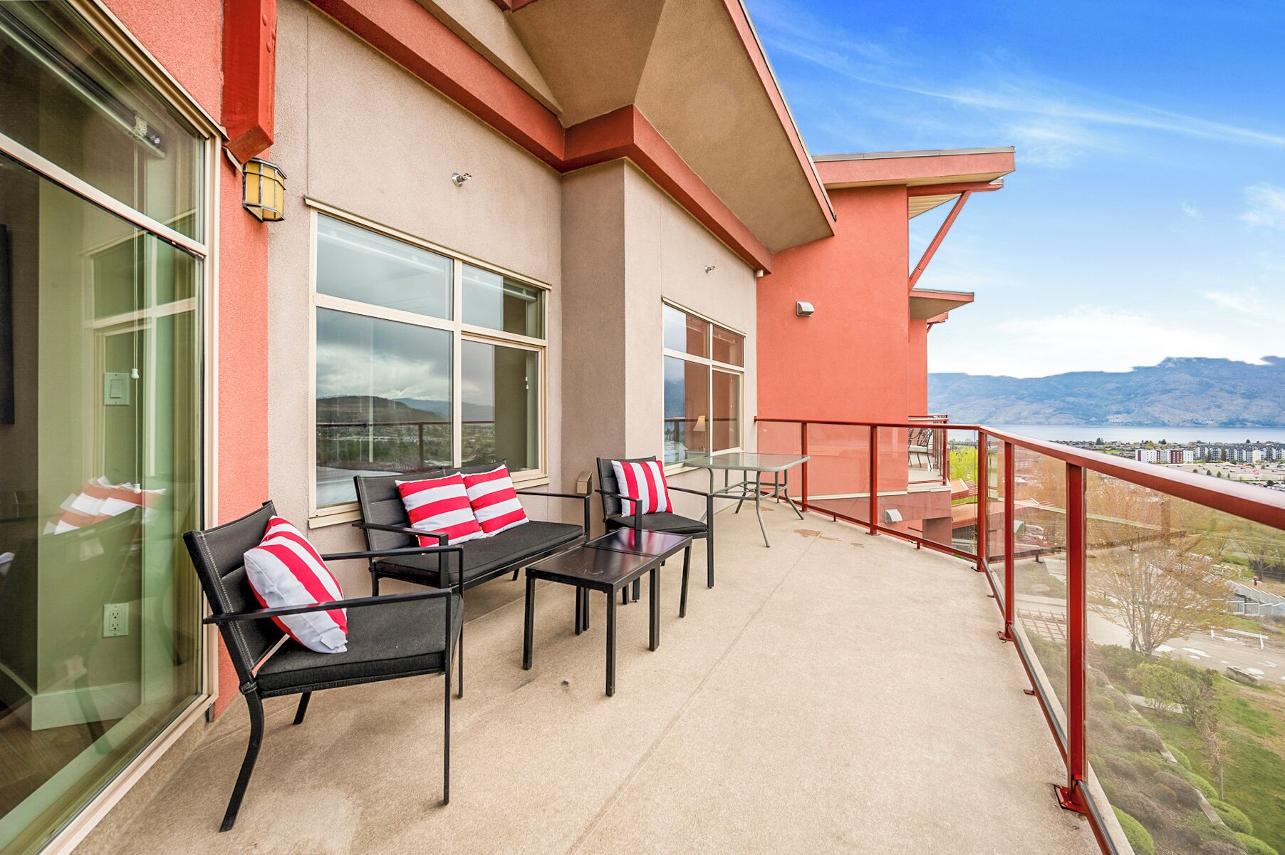 A balcony with outdoor seating, large windows, and a view of mountains.