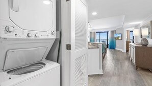 Une chambre d’hôtel moderne équipée d’un lave-linge et d’un sèche-linge à chargement frontal, d’un coin repas avec vue et d’un espace bien éclairé doté d’une grande fenêtre.
